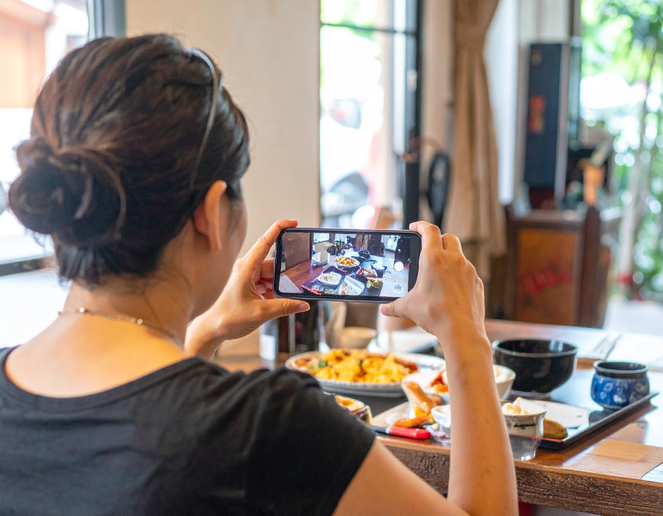スマホで料理撮影する女性